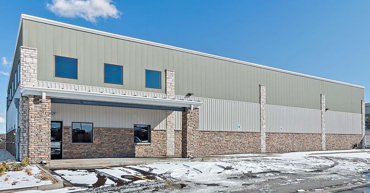 Two-story metal and stone commercial building with covered entrance and snow-dusted parking area.